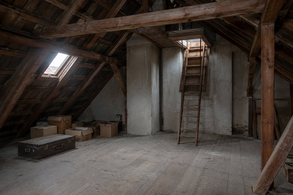 Nicht ausgebauter Dachboden mit nackten Holzdielen und einer ausgeklappten Bodentreppe.